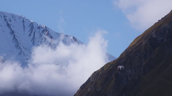 Mountains, clouds and paraglider alt