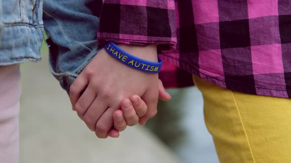 Children Hold Hands Child with Autistic Bracelet