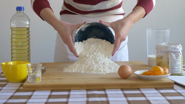 Woman pouring flour on baking board to prepare pastry