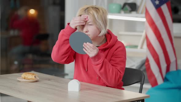 Portrait of Teen Asian Girl with Problematic Skin Applying Concealer or Makeup Foundation Sitting at alt