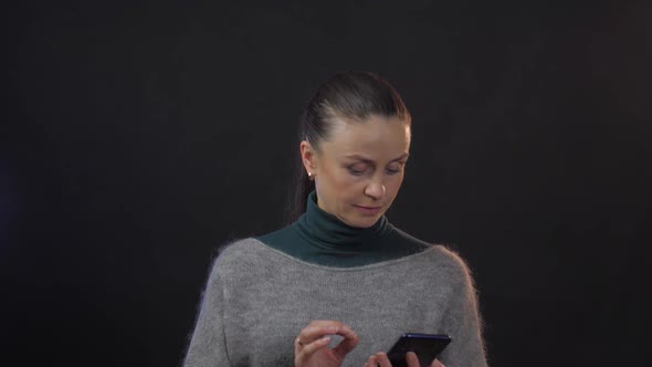 Serious Woman with Indignant Glance Looks at Smartphone alt