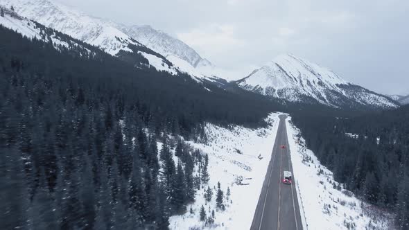 Drone video of road going through mountain ranges covered with snow in Kananaskis, Alberta, Canada alt