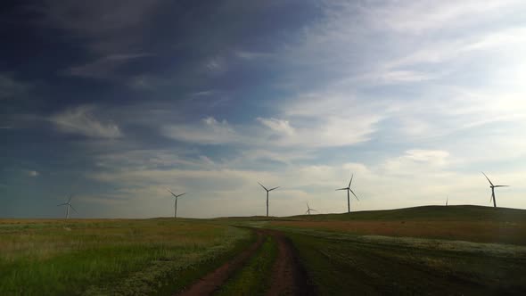 Motion the Blades of a Large Wind Turbine in a Field Against a Background of Cloudy Blue Sky Near