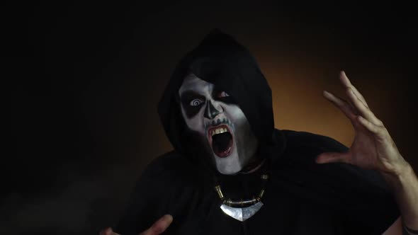 Creepy, Crazy Man with Skeleton Makeup in Hood Making Angry Faces, Shaking Head, Trying To Scare alt