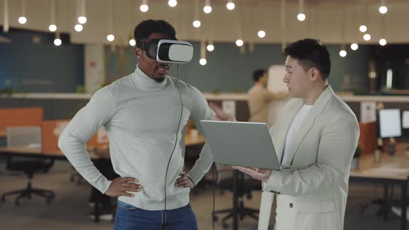 African American Businessman Testing a VR Simulator Headset While His Male Colleague Analyzing Data alt