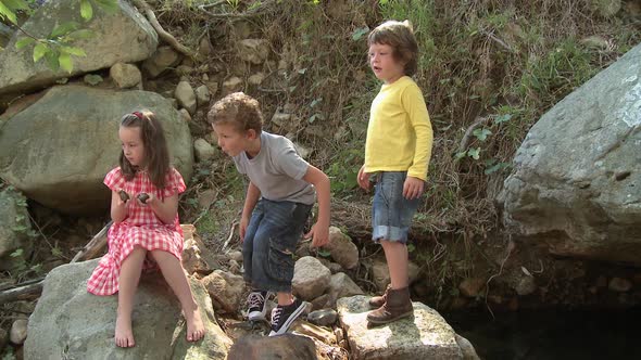 Girl sitting on rock and boys throwing stones alt