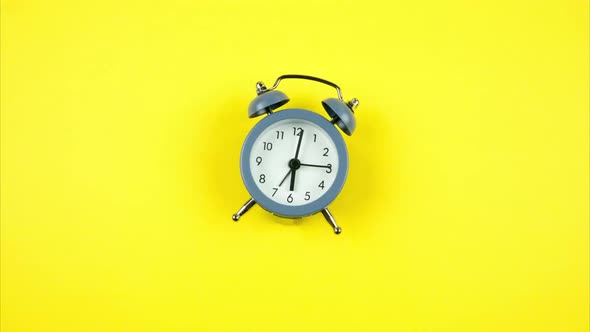 The Alarm Clock Jumps on a Yellow Background Approaching the Camera. Stop Motion alt