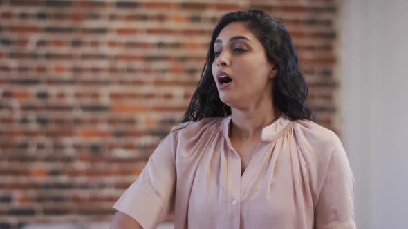 Woman sneezing on her elbow at office alt