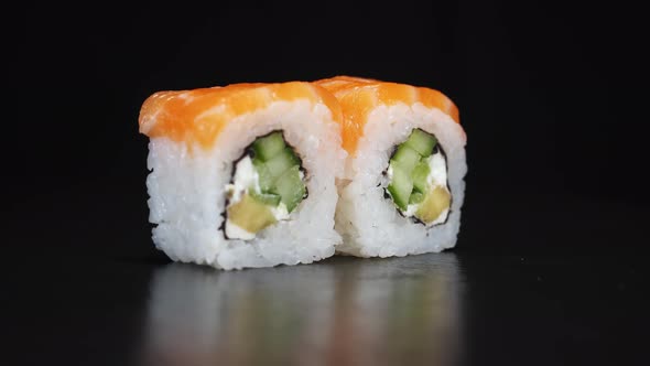 Sushi Rolls Rotate on Black Background. Close-up Shoot. Philadelphia Cheese and Salmon in Japanese