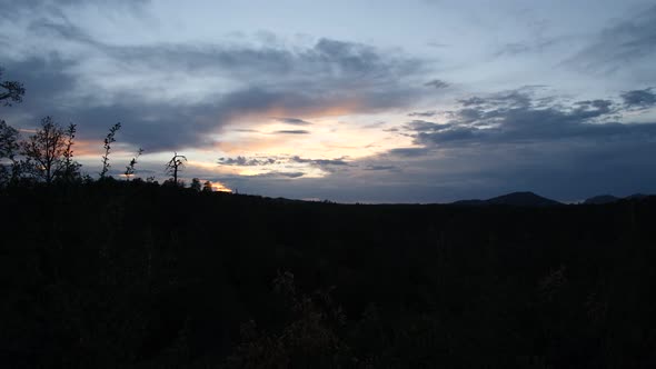 Silhouetted mountainside at sunset catching the last light. alt