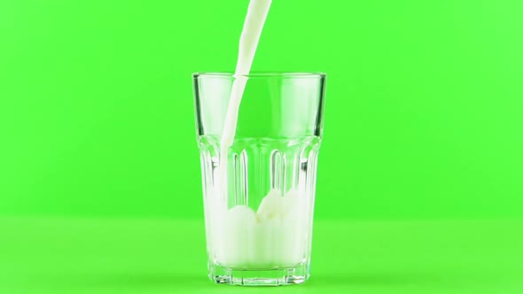 Milk Pouring Into Faceted Glass Close Up Isolated on Light Green Background Slow Motion alt