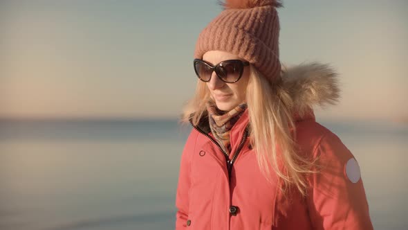 Girl In Parka Walking In Frozen Sea. Female Exploring Winter Sea Beach In Sunny Time. Cold Day. alt