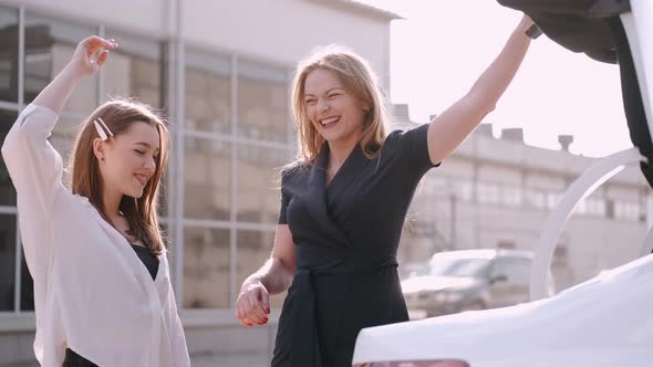 Happy Girlfriends Have Shopped and Putting Craft Shoppping Bags in a Car Trunk alt
