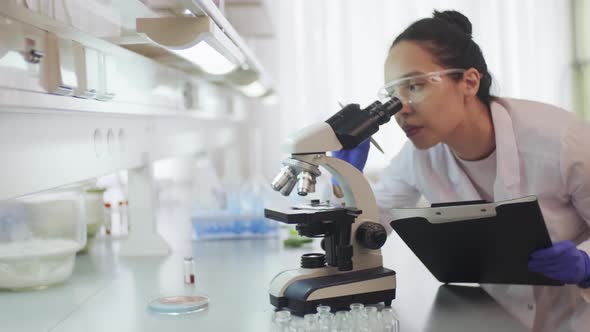 Doctor Video Footage - Video Of Female Chemist Looking Through Microscope alt