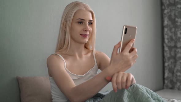 Authentic Shot of an Young Blond Woman Is Making a Video Call or Selfie with a Smartphone Before alt