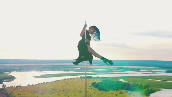 Pole Dance on Nature - Attractive Woman with Long Blue Braids in Black Clothes Posing on the Top of alt
