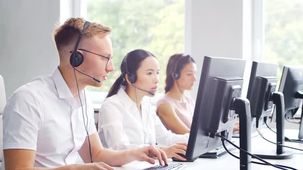 Diverse team of young professionals is working in the phone support office. alt