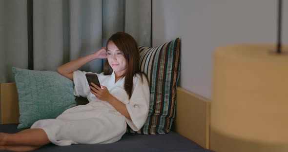 Woman Look at Mobile Phone and Sit on Sofa at Night