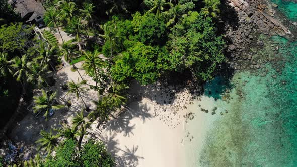 Top View of White Sand Beach with Palms Rocks on the Shore and Blue Water of