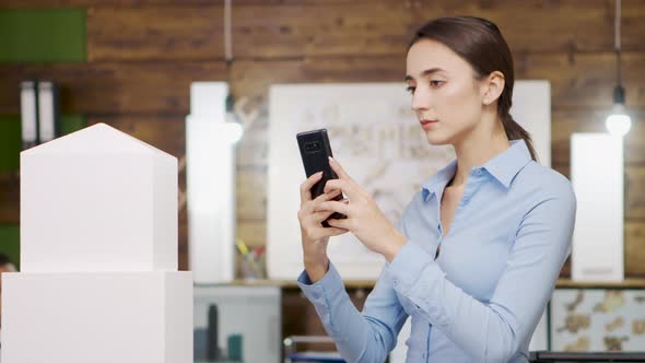 Close Up of Female Architect Taking Photos of Building Model of Sky Scraper alt