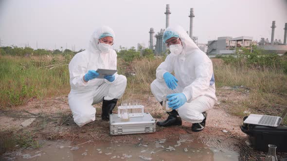 Scientist team in protective suits and masks took a sample of factory wastewater