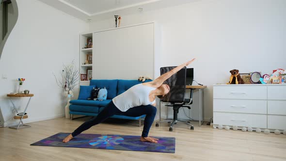 Young Woman Practicing Yoga At Home, Stretching Arm And Leg