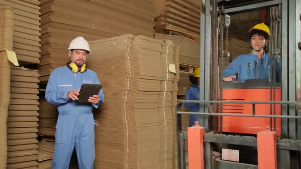 Workers team inspect stock at factory warehouse, management piles of  cardboard. alt