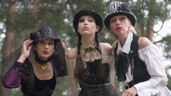 Three Concentrated Women Looking at Camera Posing in Steampunk Halloween Costumes Outdoors in Forest alt