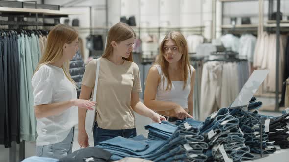 Happy Women Buying Jeans at Clothes Store alt