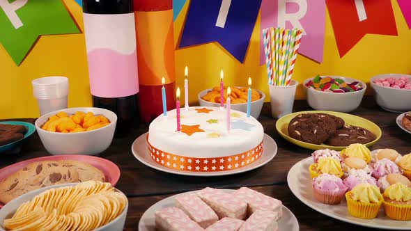 Lit Birthday Candles Cake On Table With Party Food alt