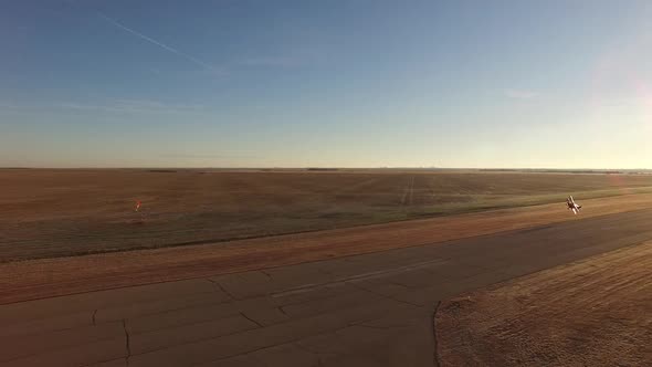 Sliding shot of an air show biplane Pitts S2B flying a knife-edge pass down the runway at a small ai alt