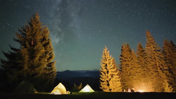 Timelapse of Hikers Resting Besides Bright Bonfire Near Illuminated Tourist Tents on Camping Site in alt