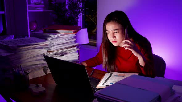 Stressed Asian woman doing overtime at home office, late time business. Workaholic people concept