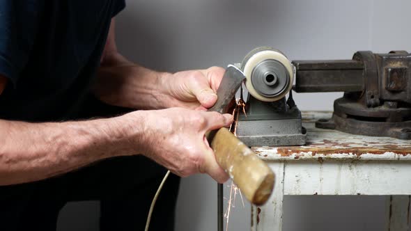 Old axe restoration. Man is sharpening an ax with a grinding machine