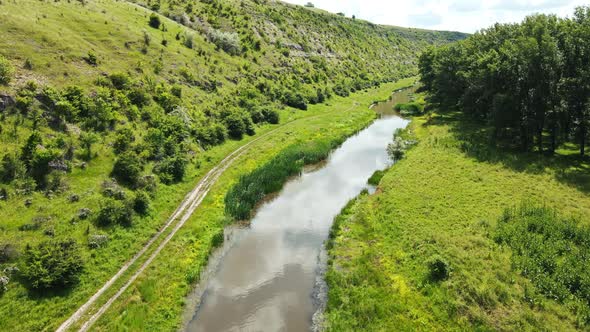 Aerial drone view of a valley in Moldova. River, a lot of greenery, cloudy sky alt