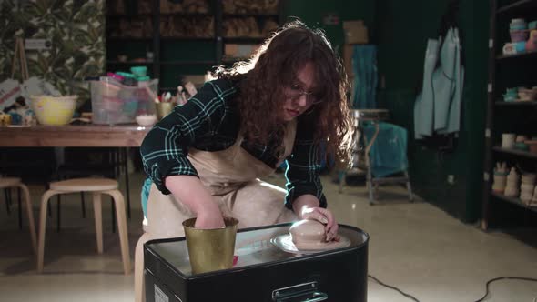 A Woman Forms Clay on a Potter's Wheel in the Art Studio alt