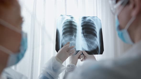 Back View Closeup of Male and Female Doctors in Covid Face Masks Examining Lungs Xray alt