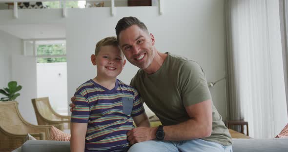 Portrait of caucasian father and son smiling in the living room at home alt
