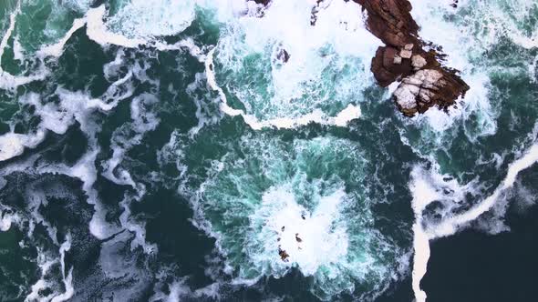 Aerial - Top down shot of turbulent ocean thrashing rocky coastline, Hermanus South Africa alt