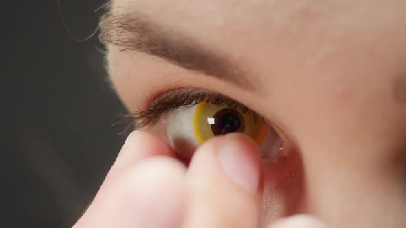 Closeup of Brown Eye Young Woman Taking Off Yellow Lens alt