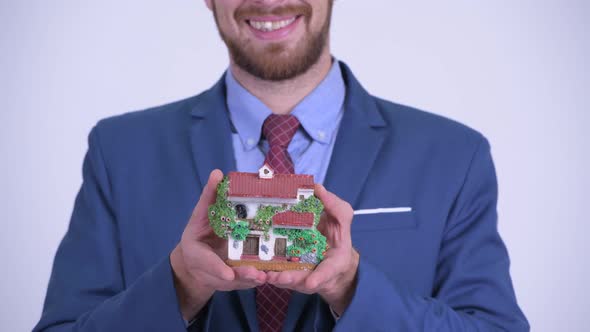 Closeup of Happy Bearded Businessman Holding House Figurine