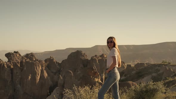 Confident Female Traveler Admiring Rocky Cliffs in Morning in Cappadocia