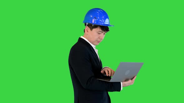 Engineer in a Suit Standing and Working on a Laptop on a Green Screen Chroma Key