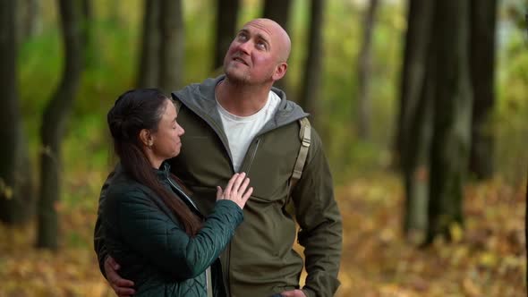 Loving Man and Woman Are Embracing Standing in Picturesque Forest at Autumn Day, Admiring Colorful alt