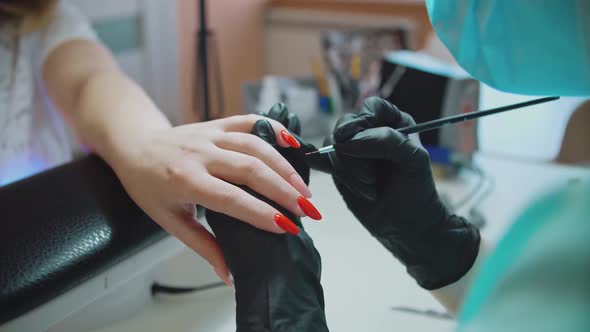 Manicure. Services of a master on manicure. The manicurist paints his nails with red gel polish. alt