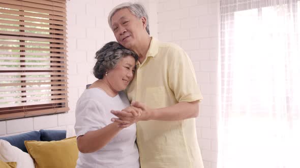 Asian elderly couple dancing together while listen to music in living room at home alt