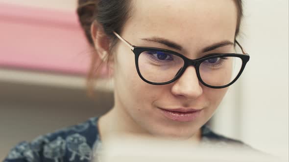 Image of Positive Woman Using Laptop and Smiling While Sitting in Office alt