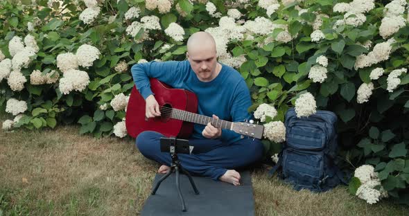 Man in with Guitar in Park Nature is Streaming Online Podcast Using Gadgets