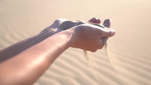 Close up of woman pouring sand running through fingers slow motion at the beach with sun flare