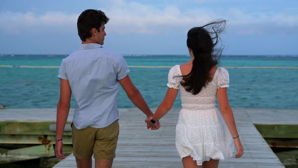 Romantic date theme. Boy and girl holding hands. Tropical island destination getaway wedding honeymo alt